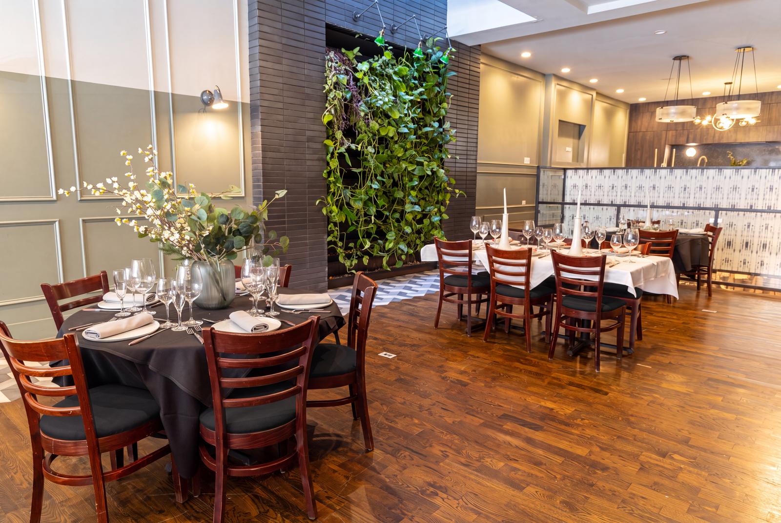 Round tables in black linen beside the living wall
