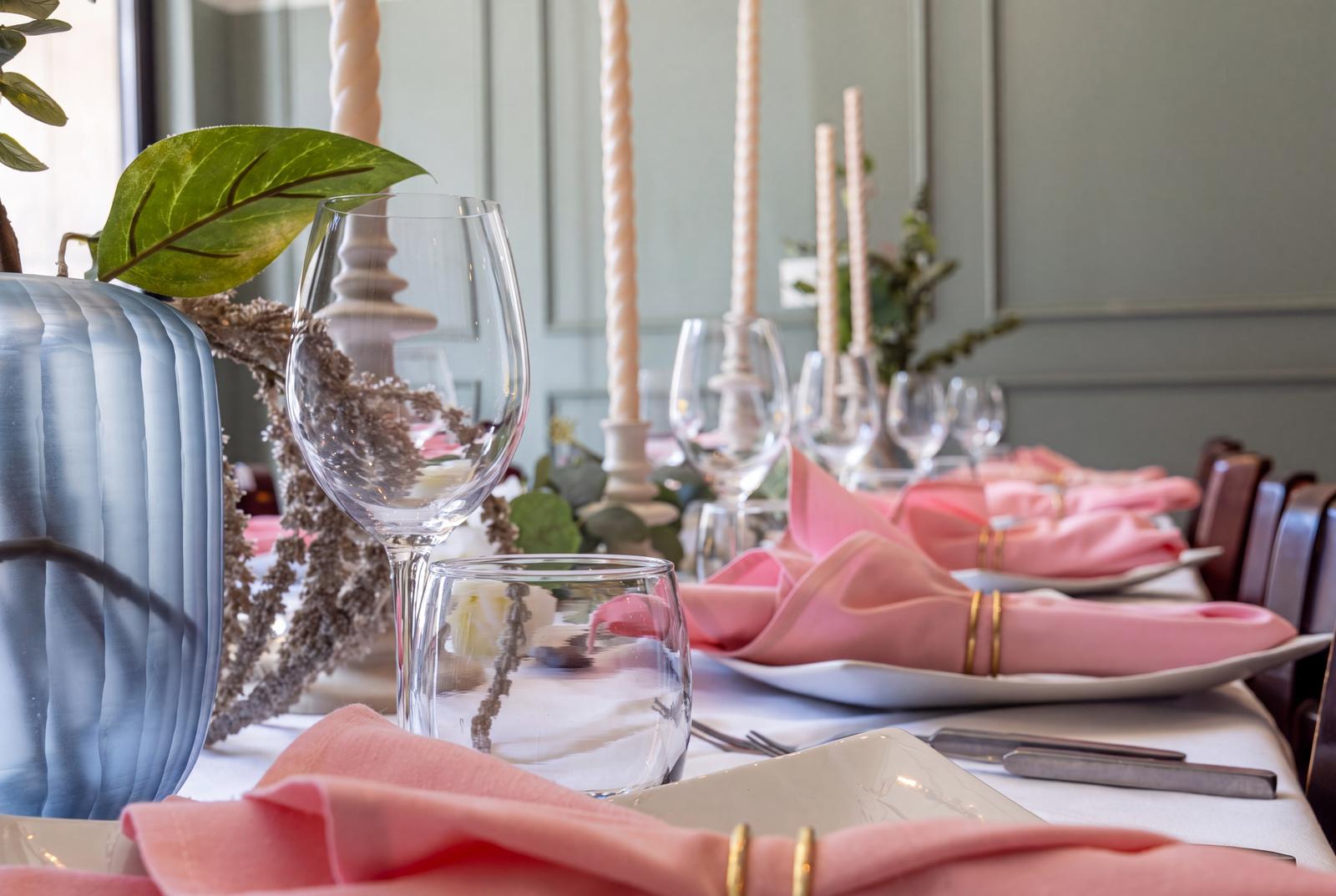 Candles, glassware and pink napkins with gold rings